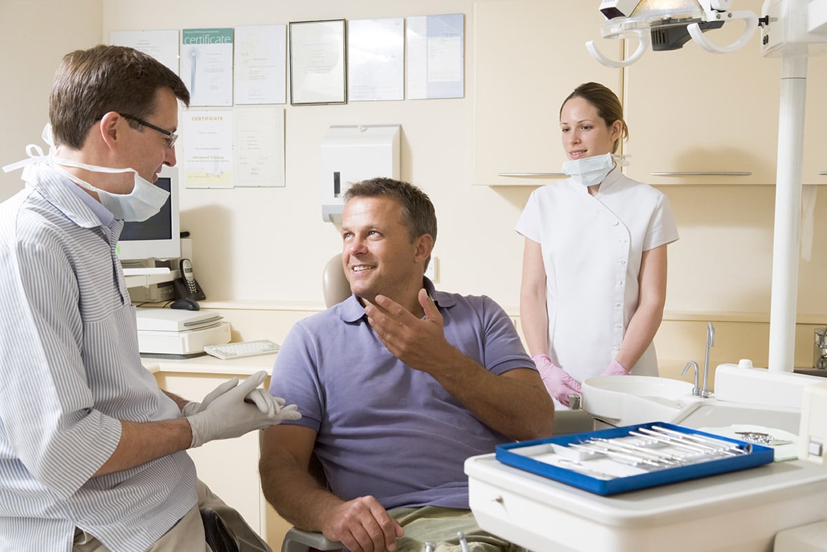 A dentist speaks with his patient about dental health habits.