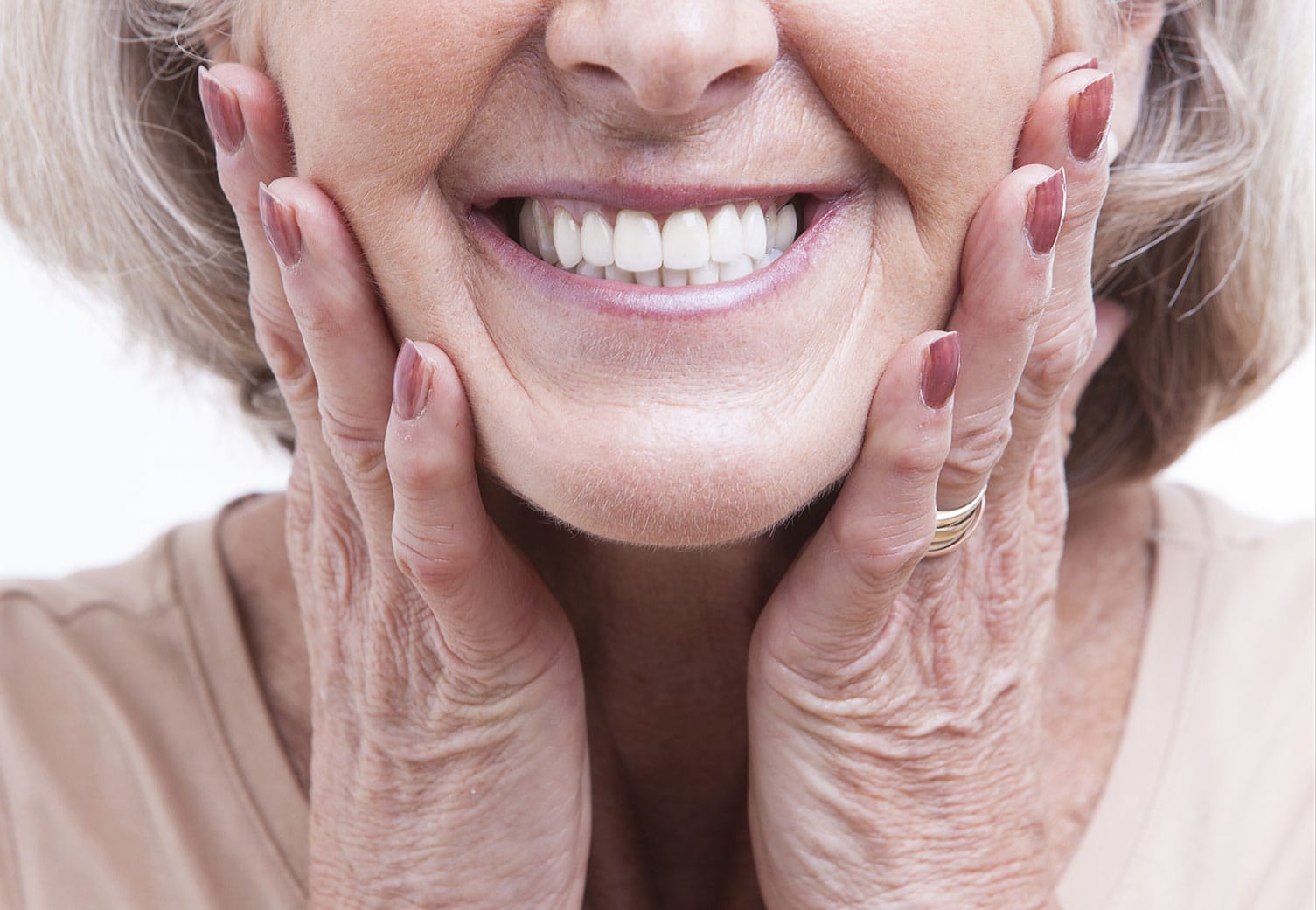 An older woman smiles, showing off her healthy and white teeth.