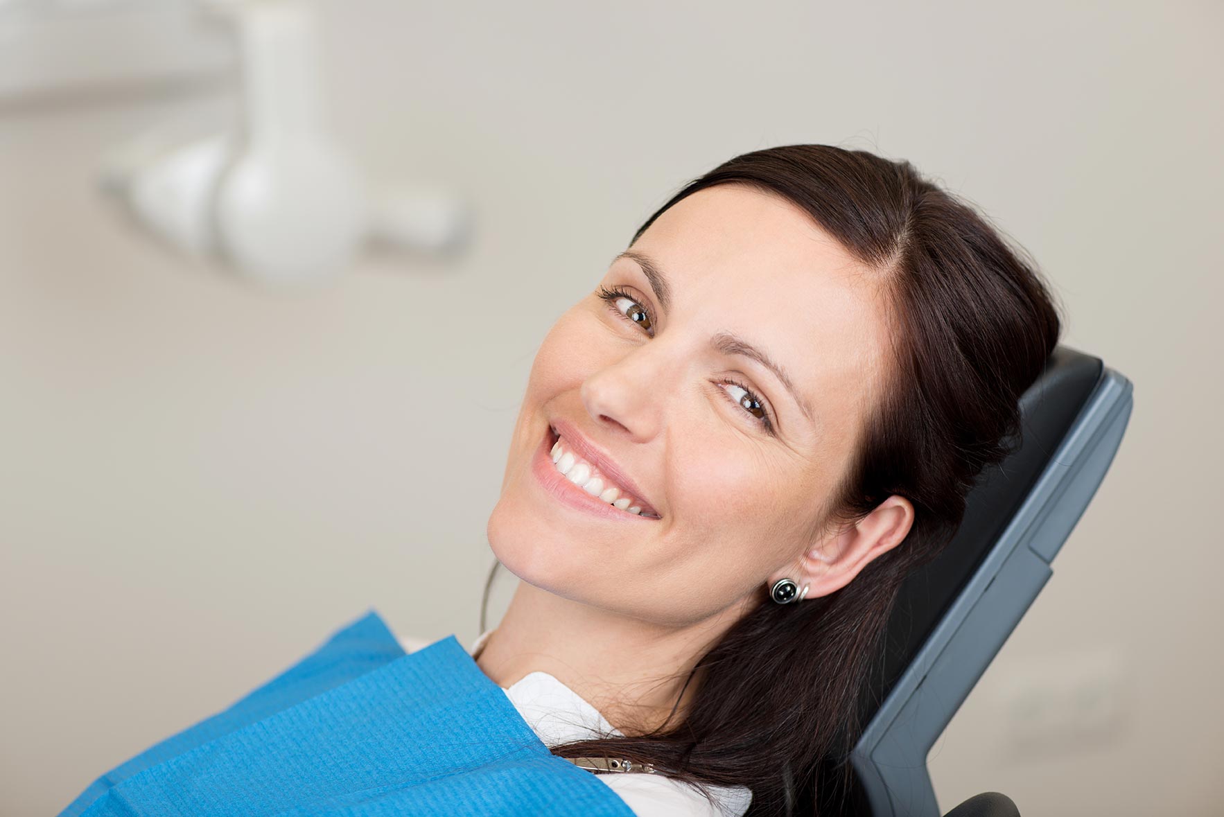 A woman sits in the dentist chair, comfortably awaiting care.